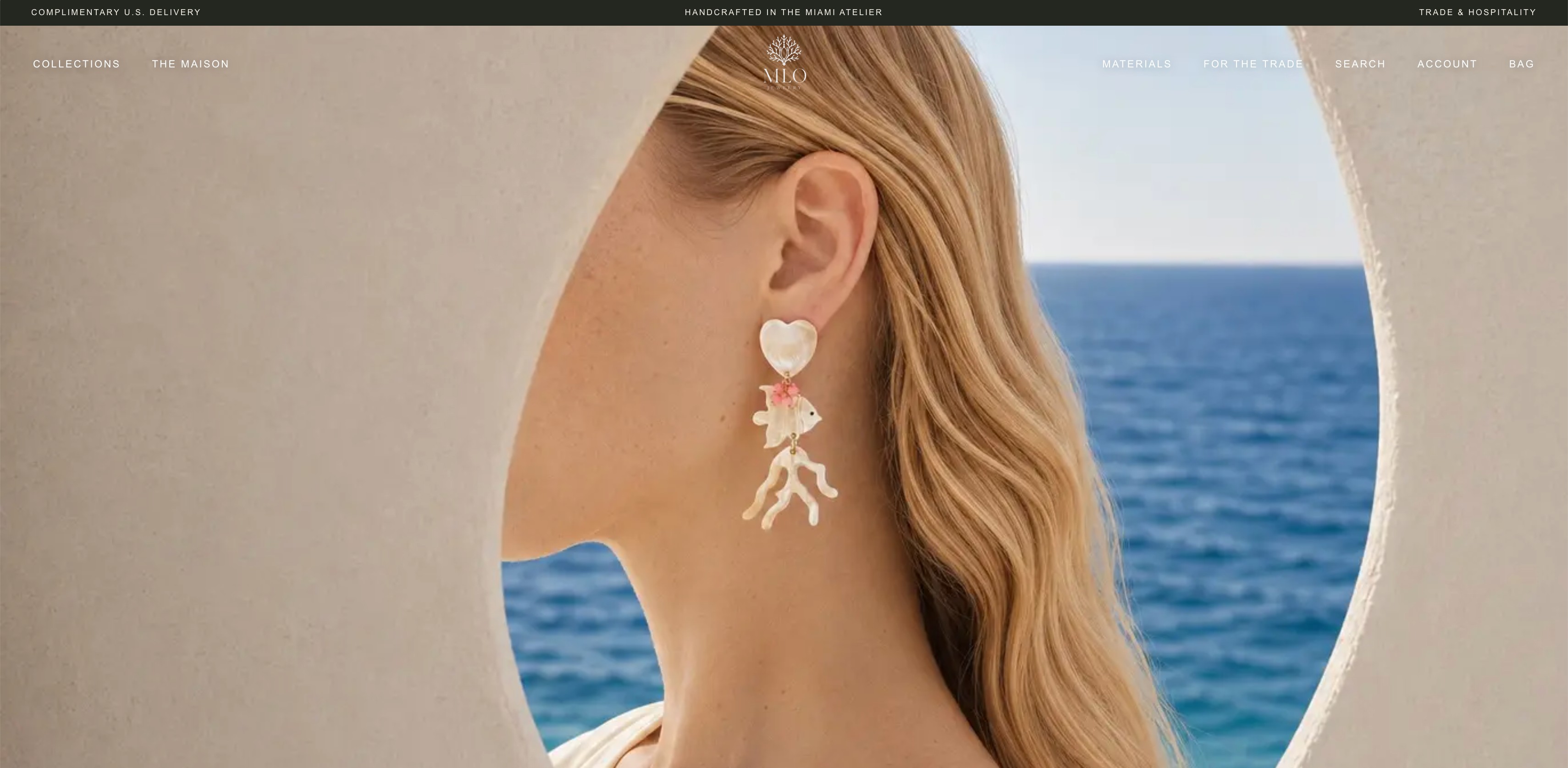 Redesigned homepage hero: a model in profile framed by a white arch over the sea, wearing a shell and coral drop earring